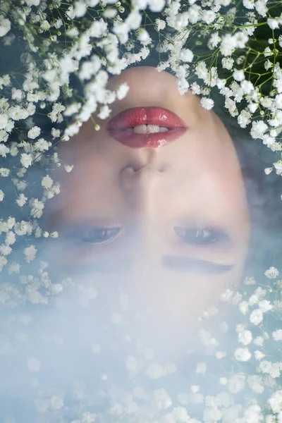 Retrato de una hermosa chica en humo con pequeñas flores blancas alrededor de su cara. Mujer y flores. Primavera . —  Fotos de Stock