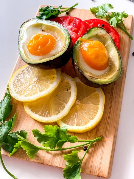 Запеченный Авокадо Яйцами Лимоном Томатными Ломтиками Деревянной Доске — стоковое фото