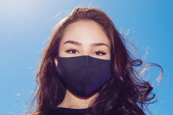 Retrato de uma jovem mulher em máscara de rosto preto protetor. — Fotografia de Stock