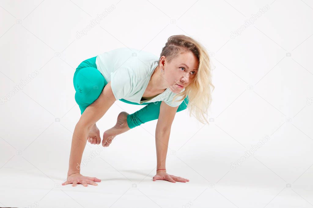 Young woman practicing yoga, balancing standing on her hands in forward-leaning exercise, bakasana pose,arm balance workout, sportswear, pants,bra,short t-shirt, in Studio room, light white background