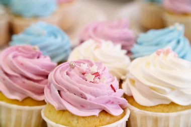 Bahar ve Paskalya şekerleriyle süslenmiş kremalı mini kekler. Ek kekler arka planda bulanık.