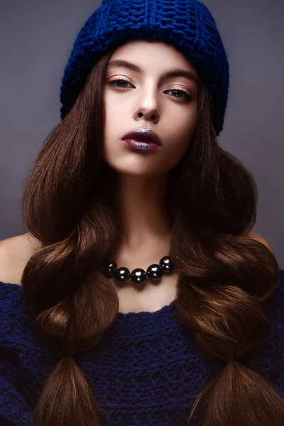 Beautiful girl in winter knitted hat blue color with a necklace around the neck of pearls. Young model with gentle make-up and silver lips. — Stock Photo, Image