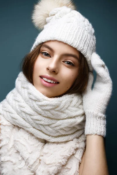 Mooi meisje in een witte gebreide muts met bont pompom. Model met zachte naakt make-up. — Stockfoto