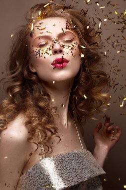 Güzel kız bir gece elbisesi ve altın bukleler. Yeni yıl glitter ve tinsel görüntüsüyle model.