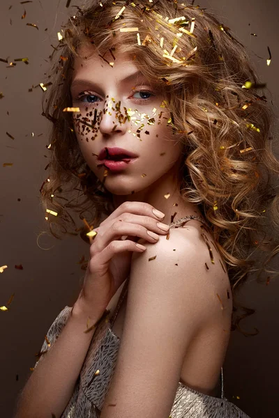 Beautiful girl in an evening dress and gold curls. Model in New Year\'s image with glitter and tinsel.
