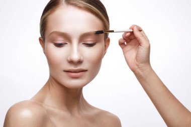 Sağlıklı cilt ve Nude makyaj ile genç kız. Güzel model makyaj uygulamak için bir fırça ile kozmetik prosedürler
