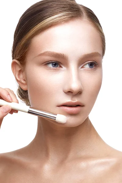 Young girl with a healthy skin and Nude makeup. Beautiful model on cosmetic procedures with a brush for applying foundation — Stock Photo, Image