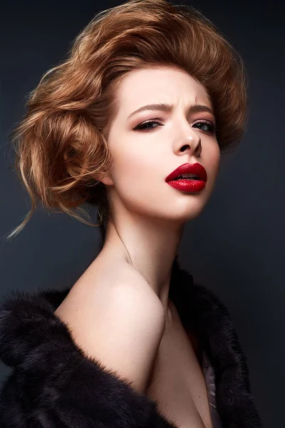 Menina jovem em um casaco de peles e maquiagem brilhante. Modelo bonito com lábios vermelhos e penteado — Fotografia de Stock
