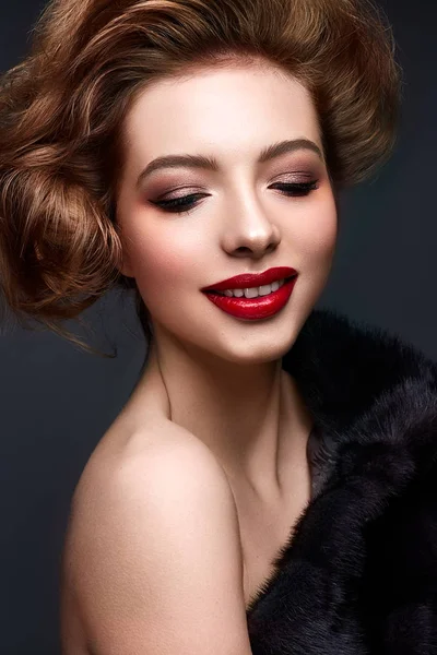 Jeune fille en manteau de fourrure et maquillage lumineux. Beau modèle avec lèvres rouges et coiffure — Photo