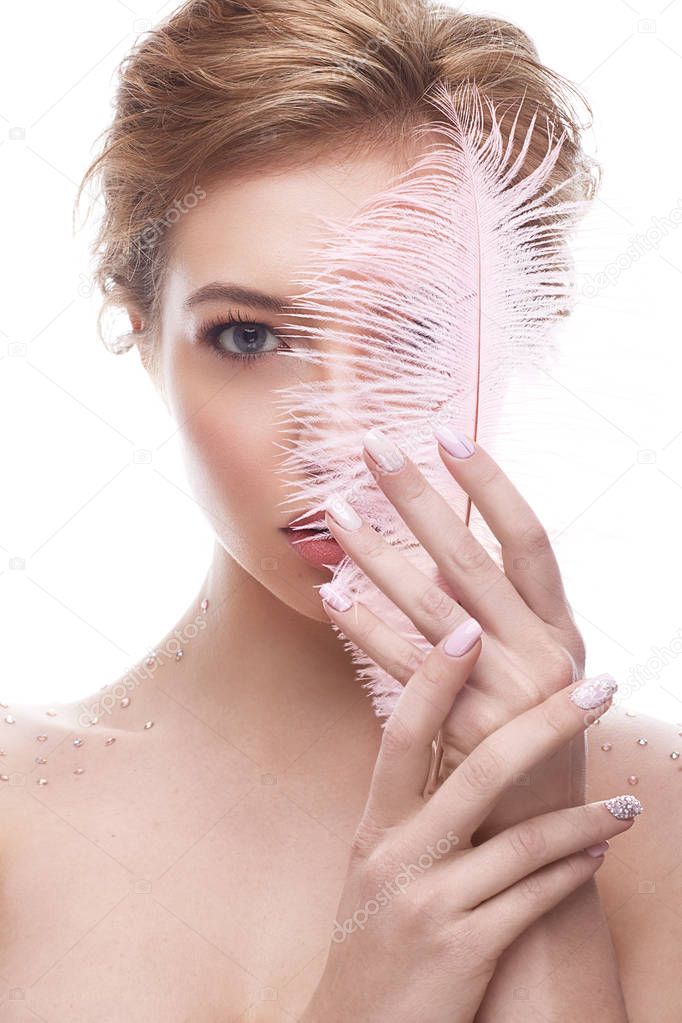 Young girl with makeup nude and pink feather in hands. Beautiful model with a gentle manicure
