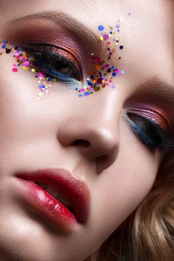 Kısa saç kesimi ve parlak yaratıcı makyaj ile genç bir kız. Kırmızı dudaklar ve yüzünde parıldıyor ile güzel bir model. Yakın çekim portre
