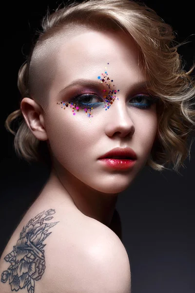 A young girl with a short haircut and bright creative makeup. A beautiful model with sparkles on the face and red lips. — Stock Photo, Image