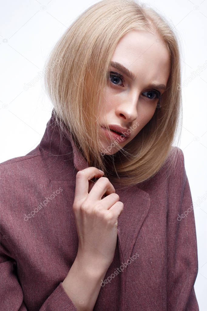 A young girl with long straight hair and nude makeup. Beautiful model in a pink coat. Blonde in a jacket. Beauty of the face