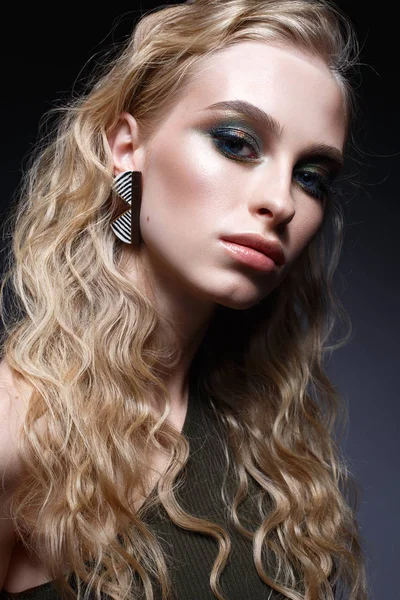 Young girl with curls and bright creative make-up. Beautiful model in earrings and green top. Beauty of the face. — Stock Photo, Image