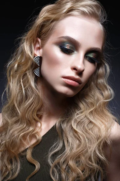 Junges Mädchen mit Locken und grellem, kreativem Make-up. wunderschönes Modell in Ohrringen und grünem Top. Schönheit des Gesichts. — Stockfoto