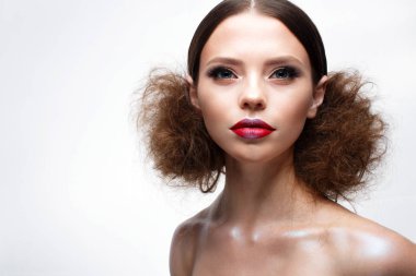 Yaratıcı parlak makyaj ve parlayan cilt ile genç kız. Güzel model bir saç modeli, gözleri ve kırmızı dudaklar okları ile. Yüz güzelliği