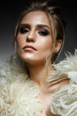 Yaratıcı makyaj ve saç modeli ile genç sarışın kız. Bir kürk manto güzel modelinde. Parlayan cilt. Akşam görüntü. Yüz güzelliği. Fotoğraf stüdyosunda alınır.