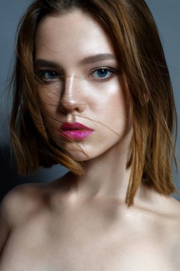 Koyu kırmızı dudaklar ve çırpınan saç ile genç bir kız. Güzel model makyaj çıplak ve ışıltılı bir cilt. Stüdyoda çekilmiş fotoğrafı. Yüz güzelliği. Kadın portre.