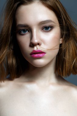 Koyu kırmızı dudaklar ve çırpınan saç ile genç bir kız. Güzel model makyaj çıplak ve ışıltılı bir cilt. Stüdyoda çekilmiş fotoğrafı. Yüz güzelliği. Kadın portre.