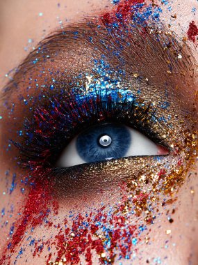 Parlak yaratıcı makyajlı, yakın çekim göz. Alışılmadık çok renkli makyaj malzemesi. Parlak cilt. Güzel surat..