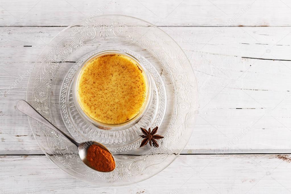 Top view image of turmeric latte over white wooden table