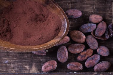 Kakao tozu ve rustik ahşap arka plan üzerinde fasulye