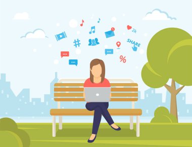 Parkta bankta oturan ve laptop ile çalışan genç kadın