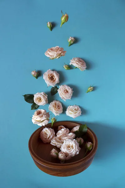 Creative layout of wooden tableware with roses on a blue background. Levitation of the flower. The magic and tenderness. Beautiful levitation. Flatley. Vertical orientation. Happy mother\'s day