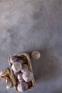 Beton arkaplanda bir sepette sarımsak. Açık sarımsaklı karanfil. Plastik yok. Mesaj için yer var. Uzayı kopyala Yukarıdan manzara. Düz çizgi. Dikey oryantasyon. Salgın sırasında bağışıklık sisteminin kaldırılması.