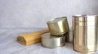 Uzun vadeli depolama ürünleri. Hafif arka planda konserve çelik yemek kutuları ve makarna. Makarna, spagetti. Pandemik koronavirüs sırasında karantina altındaki stoklar. Uzayı kopyala Yemek teslimatı konsepti. Bağış