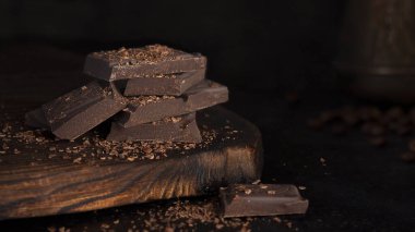 Tahta üzerinde acı çikolata olan pankart. Koyu arkaplanda çikolata ve kahve. Çikolata parçacıklı. Alçakgönüllülük. Uzayı kopyala Yatay oryantasyon. Kafeler ve restoranlar için çekim kavramı