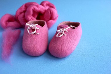 Mavi arka planda yeni doğmuş bir bebek için parlak pembe fuşya yünlü patik.