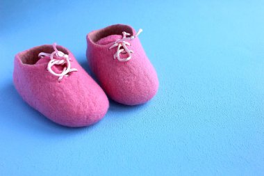 Mavi arka planda yeni doğmuş bir bebek için parlak pembe fuşya yünlü patik.