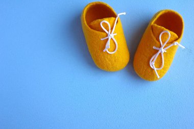 Mavi arka plandaki bebek için keçeli yünden yapılmış sarı çizmeler.