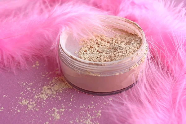 Makeup loose mineral powder for fair skin beauty shade of ivory and pink flamingo feathers on a pink background in the dressing room