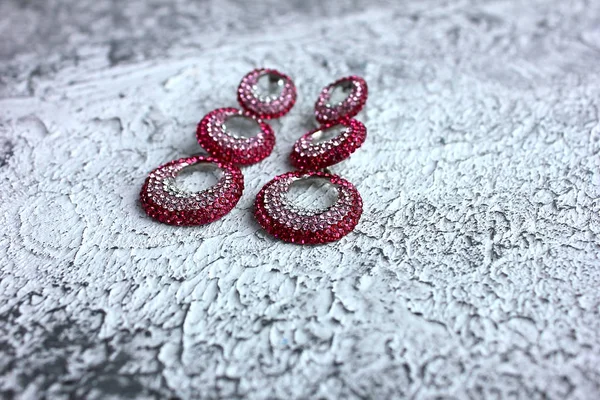 ピンク色の結晶を持つ長いヴィンテージピンクのイヤリングは レトロなヴィンテージパターンを持つグレー 白の背景に宝石やダイヤモンドのリングを形成します — ストック写真