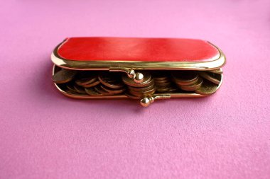 Kırmızı-pembe antika aksesuar cüzdan içi altın sikkelerle dolu, sıcak pembe bir fuşya arka planında yatıyor.