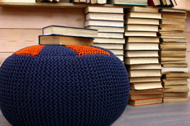 Bir yığın kitap, yerde ve kitaplıkta bir sürü kitap. Ahşap bir duvarın arkasına yumuşak bir pouf ördüm. İç eko tarzı oda 