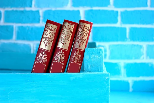 Trzy Czerwone Książki Tle Niebieskiej Cegły Ściany Połączenie Czerwonych Niebieskich — Zdjęcie stockowe