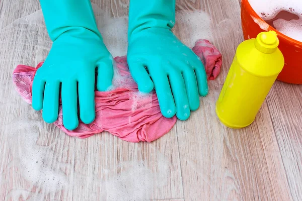 To wash the floor, linoleum, parquet. Hand in rubber gloves, a bucket of soapy water for mopping and damp cleaning, wet pink rag , yellow plastic bottle with detergent