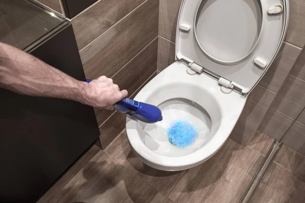 Человек наливает чистильщик в унитаз, дезинфицирует туалет. . — стоковое фото