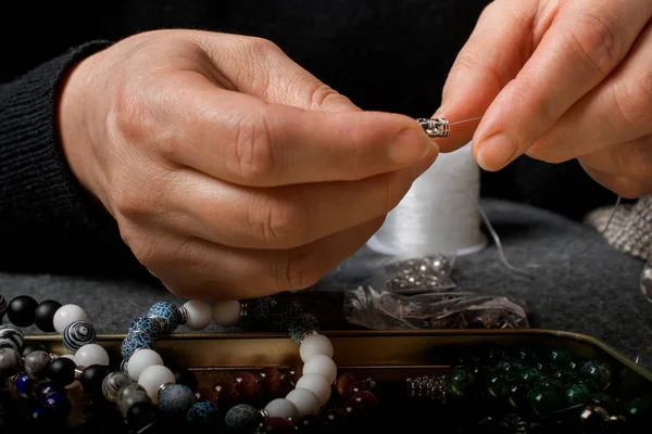 Woman making homemade beaded  bracelet, closeup.