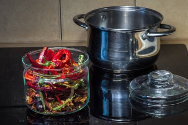 Mutfakta, indüksiyon hobında. Renkli biberli cam kavanoz.. 