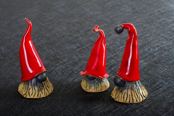 Elfos de Natal cerâmicos em chapéus vermelhos em um fundo preto — Fotografia de Stock