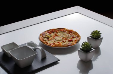 Beyaz bir masada küçük bir pizza tabağı.