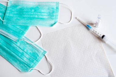 Koruyucu maskeler, not kağıdı, şırınga ve aşı.
