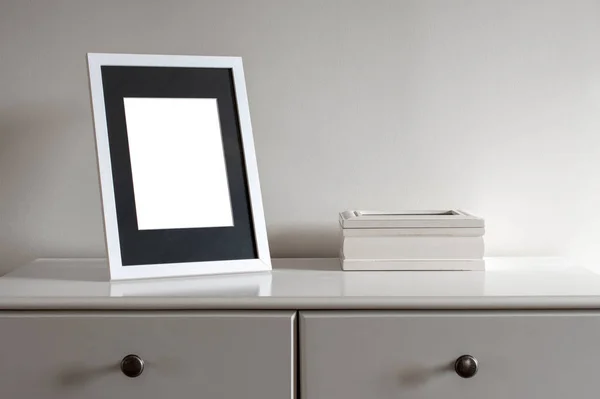 Maqueta de marco blanco y caja de madera en una cómoda blanca . — Foto de Stock