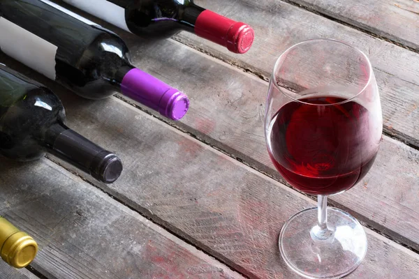Una Copa Vino Tinto Botellas Vino Sobre Fondo Madera Viejo —  Fotos de Stock