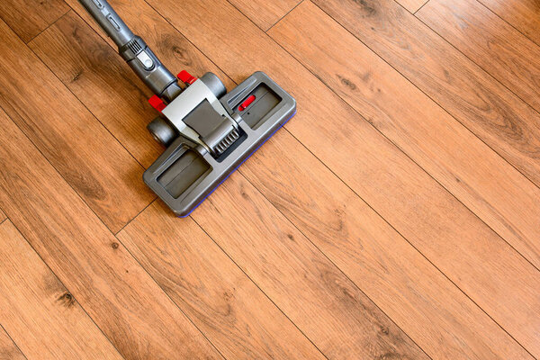 Modern vacuum cleaner cleaning parquet floor. Top view.