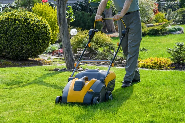 芝生の芝刈り機で庭の草を刈る男 — ストック写真